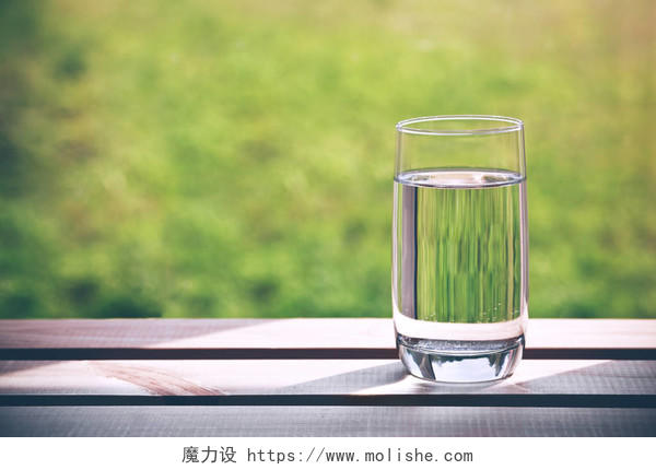 在绿色自然背景的纯净的水玻璃
